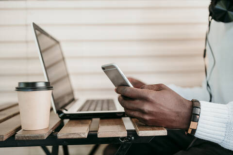 Mann mit Laptop und Smartphone in einem Cafe, lizenzfreies Stockfoto