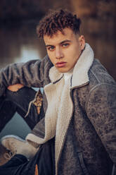 Fashionable young man with blue eyes on jetty against lake - ACPF00972