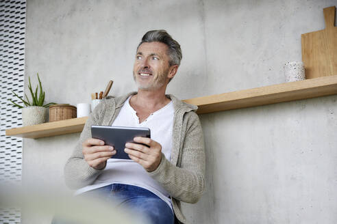 Älterer Mann lächelt bei der Verwendung eines digitalen Tablets - FMKF06924
