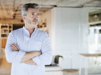 Businessman looking away while standing with arms crossed - FMKF06940