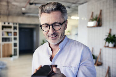 Businessman smiling while talking on mobile phone - FMKF06955