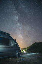 Camper van parked near mountain against star sky - MPPF01339
