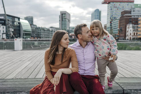 Heterosexual couple with their daughter on bridge in city - OGF00679