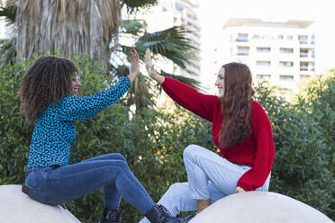 Lächelnde junge Frauen, die sich im öffentlichen Park gegenseitig 