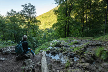 Wanderin auf einem Felsen sitzend bei der Erkundung der Schwäbischen Alb, Deutschland - FDF00283