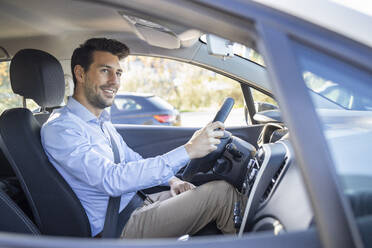 Male entrepreneur with hand on steering wheel sitting in car - IFRF00190