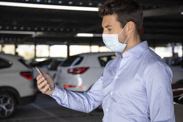 Male entrepreneur using mobile phone in parking lot during pandemic - IFRF00200