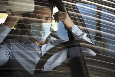 Geschäftsmann mit Gesichtsschutzmaske im Auto während COVID-19 - IFRF00201