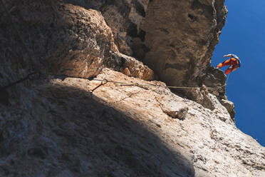 Determinant sportsman climbing mountain on sunny day - JAQF00020