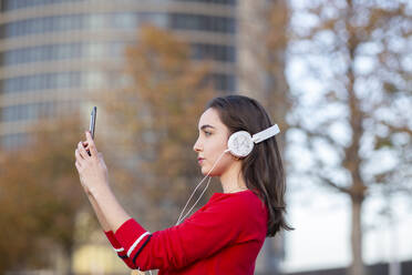 Woman with headphones taking selfie on mobile phone - JCCMF00250