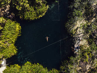 Luftaufnahme einer Frau beim Schwimmen in einer Cenote - JMPF00744