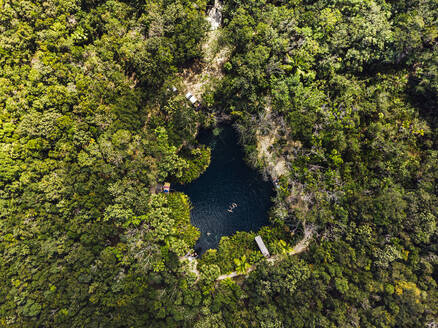 Aerial view of cenote surrounded by green lush jungle - JMPF00745