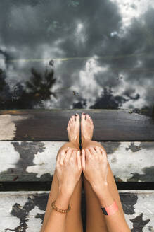 Nackte Beine einer Frau, die sich auf den Stufen einer unterirdischen Cenote entspannt - JMPF00748