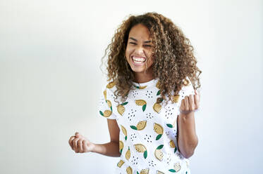 Happy afro young woman triumph gesturing against white wall - KIJF03470