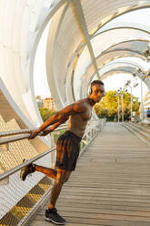 Male athlete leaning on railing while standing over bridge - IFRF00206