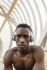 Männlicher Sportler, der über eine Brücke mit Kopfhörern Musik hört - IFRF00209