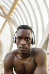 Male athlete listening music through headphones over bridge - IFRF00209