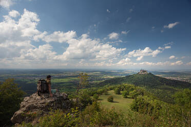 Wanderer mit Blick auf die Burg Hohenzollern, sitzend auf einem Berg auf der Schwäbischen Alb, Deutschland - FDF00318