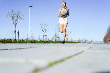 Athlete exercising while running on footpath during sunny day - PGF00274