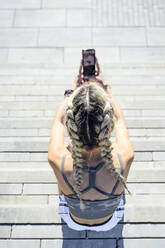 Sportswoman using mobile phone while sitting on staircase - PGF00275