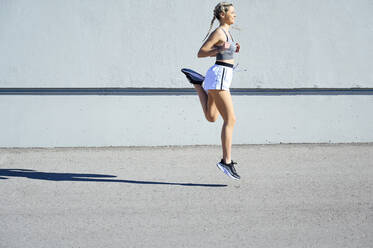 Junge Sportlerin läuft an einem sonnigen Tag gegen die Wand - PGF00280
