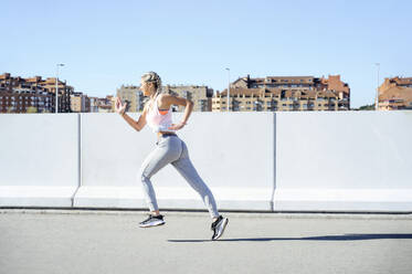 Sportlerin beim Laufen auf dem Fußweg an einem sonnigen Tag - PGF00296