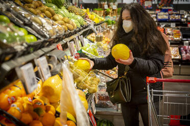 Mature woman buying fruits in supermarket during COVID-19 - NGF00735