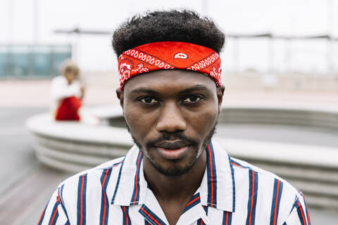 Man wearing headband staring while sitting outdoors stock photo