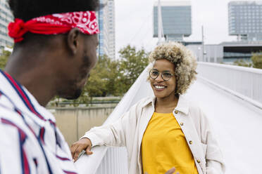 Lächelnde Frau steht mit männlichem Freund auf einer Brücke in der Stadt - XLGF00926