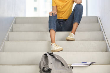 Studentin sitzend mit Büchern und Tasche an der Universität - AODF00042