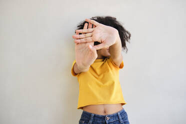 Frau zeigt Stop-Geste, während sie gegen eine weiße Wand steht - AODF00046