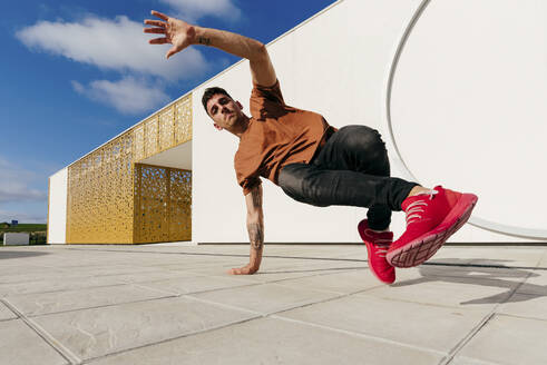 Young man dancing on footpath during sunny day - MARF00054