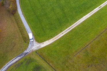 Drohnenansicht eines Lieferwagens, der im Herbst eine Kreuzung auf dem Land passiert - WWF05736