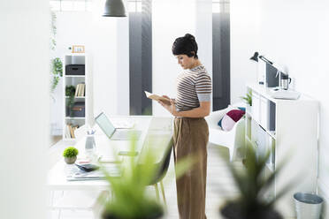 Portrait of businesswoman browsing documents in front of office table - GIOF10091