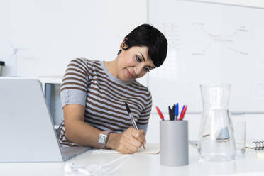 Portrait of businesswoman doing paperwork at office desk - GIOF10093