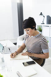 Portrait of businesswoman doing paperwork at office desk - GIOF10094
