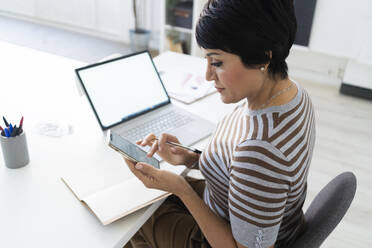 Portrait of businesswoman using smart phone at office desk - GIOF10099