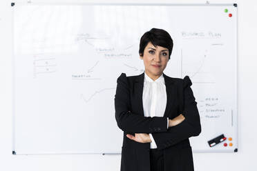 Porträt einer Geschäftsfrau, die vor einem Whiteboard im Büro posiert - GIOF10117