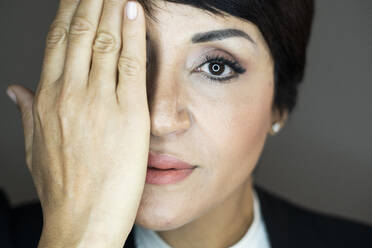 Porträt einer Geschäftsfrau, die ihr Gesicht mit der Hand bedeckt - GIOF10144