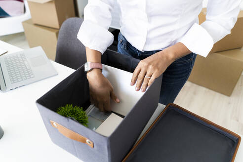 Hände einer Geschäftsfrau beim Packen von Kisten vor einem Büroumzug - GIOF10147