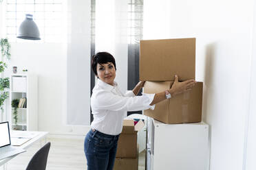 Portrait of businesswoman organizing office before relocation - GIOF10150