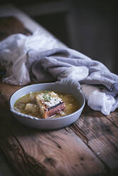 From above bowl with palatable French onion soup near towel on wooden surface - ADSF19268