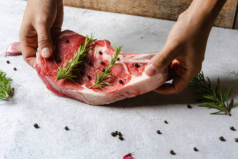 Unbekannter Koch bereitet in der Küche rohes Rindersteak mit Knochen für das Abendessen vor - ADSF19274