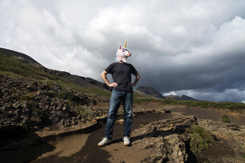 Mann mit Einhornmaske, stehend mit Hand auf der Hüfte in Laugarvatnshellir, Reydarbarmur, Island - NEKF00050