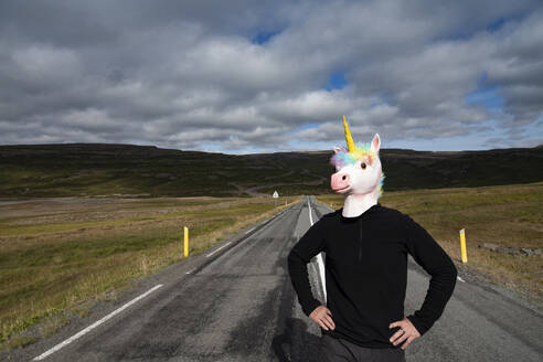 Mann mit Einhorn-Gesichtsmaske steht auf der Autobahn - NEKF00057