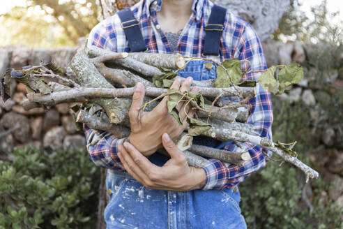 Young man holding bunch of sticks - JPTF00614