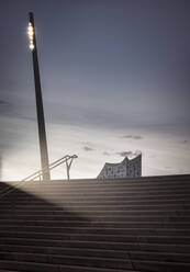 Deutschland, Hamburg, Leere Treppen in der Abenddämmerung mit Elbphilharmonie im Hintergrund - RJF00833