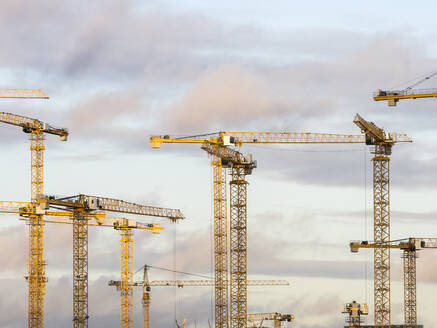 Construction cranes standing against sky at dusk - RJF00836