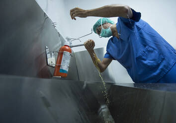 Männlicher Chirurg beim Händewaschen im Waschbecken eines Krankenhauses - JCMF01689