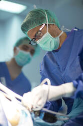 Männlicher Chirurg mit Mitarbeiter bei der Operation eines Patienten auf der Intensivstation eines Krankenhauses - JCMF01691
